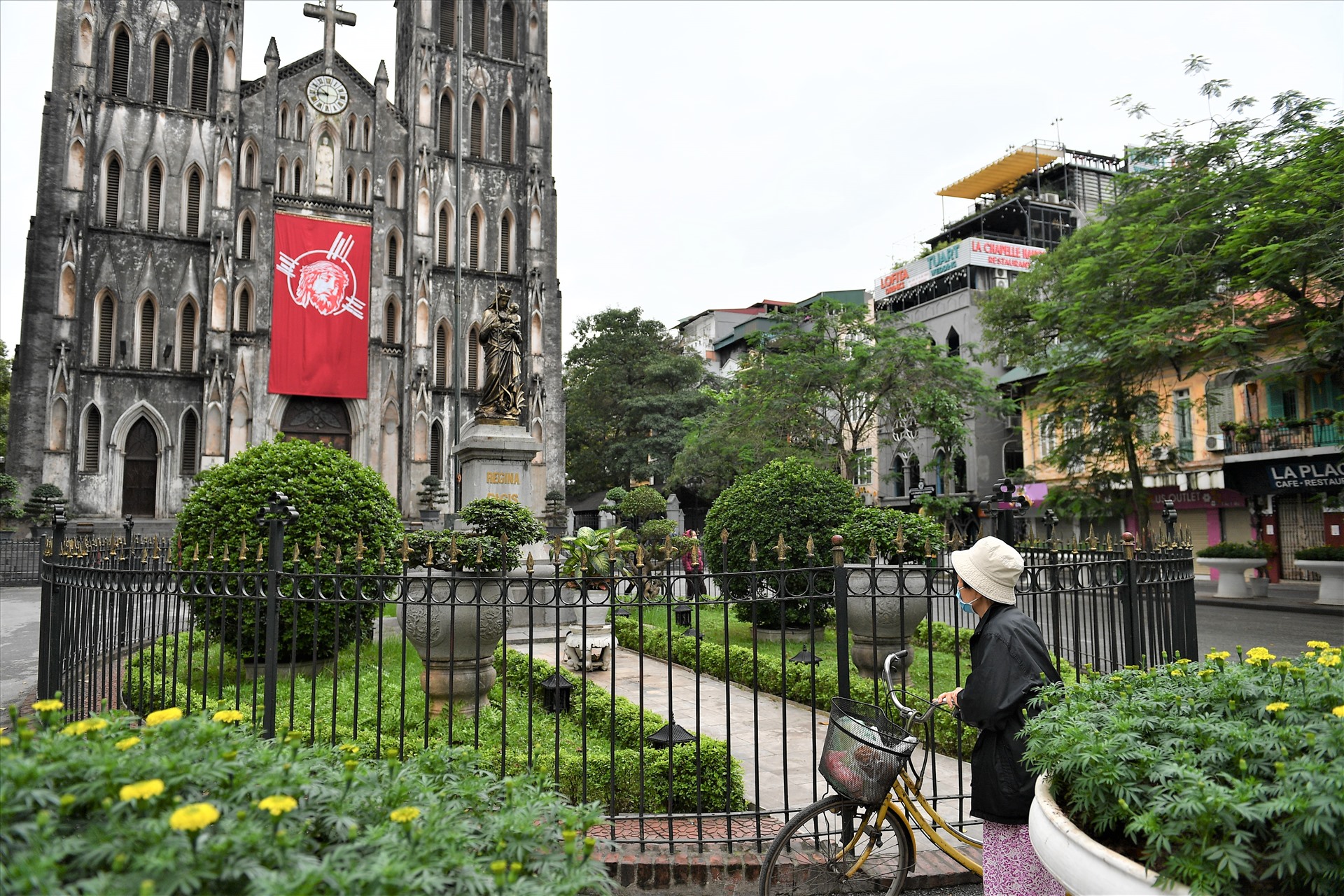 Nhà Thờ Lớn chủ nhật thường có nhiều khóa lễ, nay tạm đóng cửa. Sáng sớm, một người đàn bà đứng ở ngoài hướng về tượng Chúa.