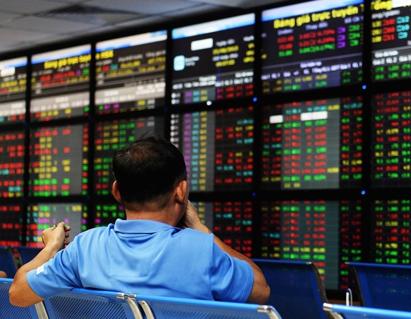 Một nhà đầu tư theo dõi giá cổ phiếu trên một bảng điện tử tại một sàn giao dịch chứng khoán địa phương ở Hà Nội. Ảnh: AFP