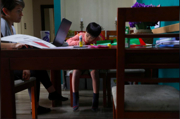 Cậu học sinh Renato, 10 tuổi, may mắn có điều kiện học tập tại nhà qua mạng internet dưới sự hướng dẫn của mẹ, tại Chile, ngày 30.3. Ảnh: Reuters