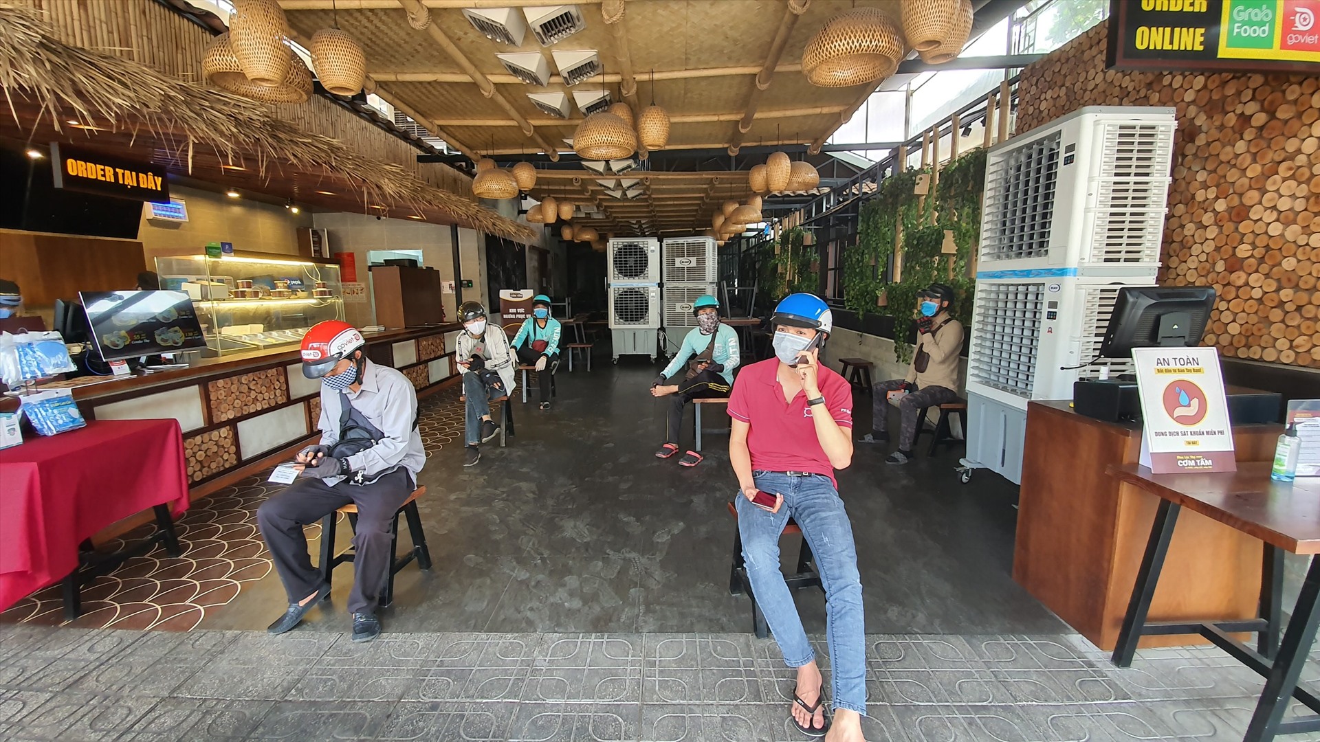 Một quán cơm lớn trên đường Ung Văn Khiêm (quận Bình Thạnh), sắp xếp chỗ ngồi cho khách hàng và shipper trong lúc chờ lấy cơm đảm bảo khoảng cách tối thiểu 2m.
