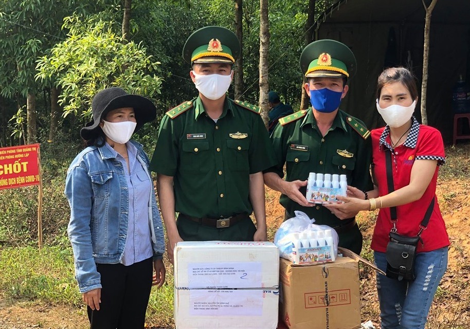 Chị Huệ (áo đỏ, bìa phải ảnh) - vợ của thượng úy Phan Thanh Tùng tặng nước rửa tay sát khuẩn và khẩu trang cho chốt phòng dịch thuộc Đồn Biên phòng Hướng Lập. Ảnh: Phan Vĩnh.
