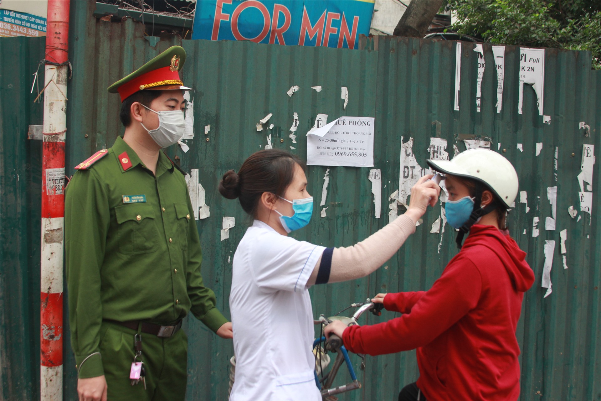 Trung úy Trần Văn Sơn và cán bộ y tế kiểm tra thân nhiệt của người dân ra đường.