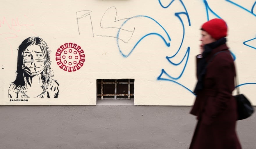 Graffiti một người phụ nữ đeo khẩu trang cạnh hình ảnh của virus Corona ở Berlin, Đức. Ảnh: Getty Images.