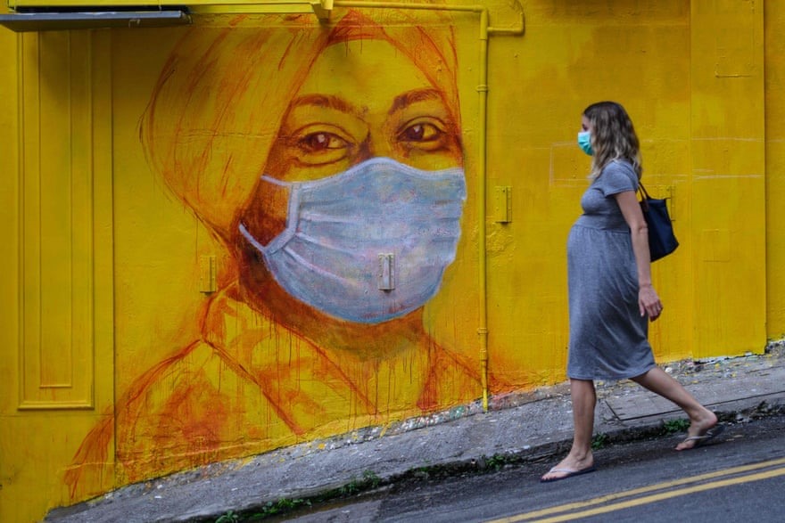 Một phụ nữ mang thai đeo khẩu trang đi ngang qua bức tranh tường ở Hong Kong, Trung Quốc. Ảnh: Getty Images.