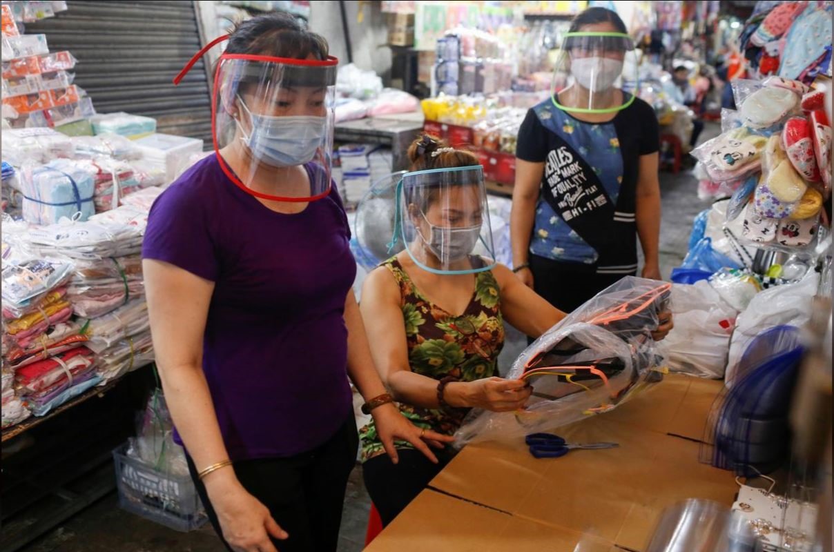Các bạn bè tiểu thương của chị Linh ở chợ Bà Chiểu đang đeo các tấm che mặt mà họ cùng góp công thực hiện. Ảnh: Reuters