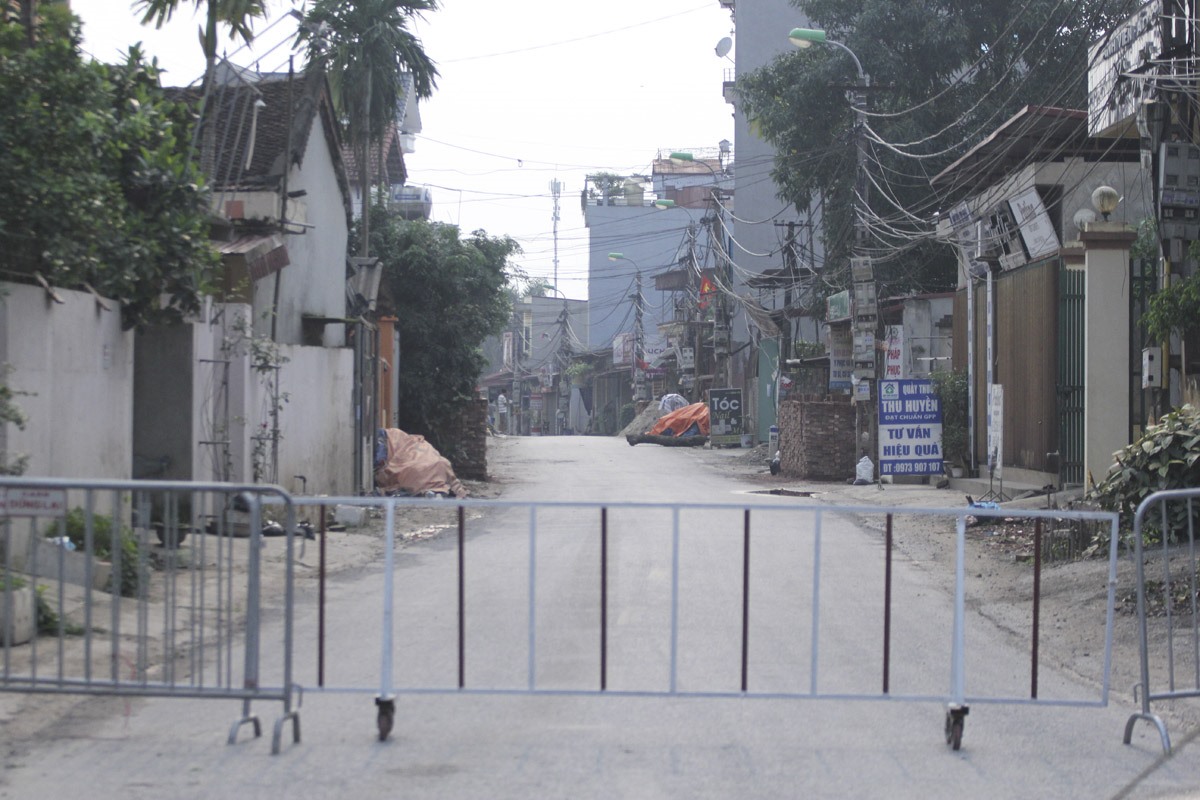 Hàng rào barie được dựng lên để hạn chế người dân đi lại ra khỏi khu vực thôn.
