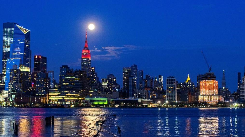 Siêu trăng trên Tòa nhà Empire State, quận Manhattan, thành phố New York, Mỹ trong bối cảnh tòa nhà đang thắp sáng để cổ vũ những người mắc COVID-19. Ảnh: Reuters.