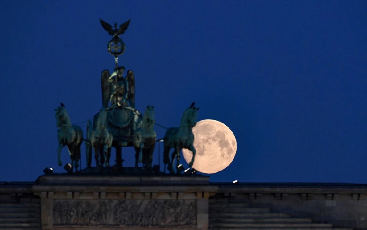 Mặt trăng phía sau tượng chiến xa tứ mã ở Brandenburg Gate, Đức. Ảnh: Reuters.
