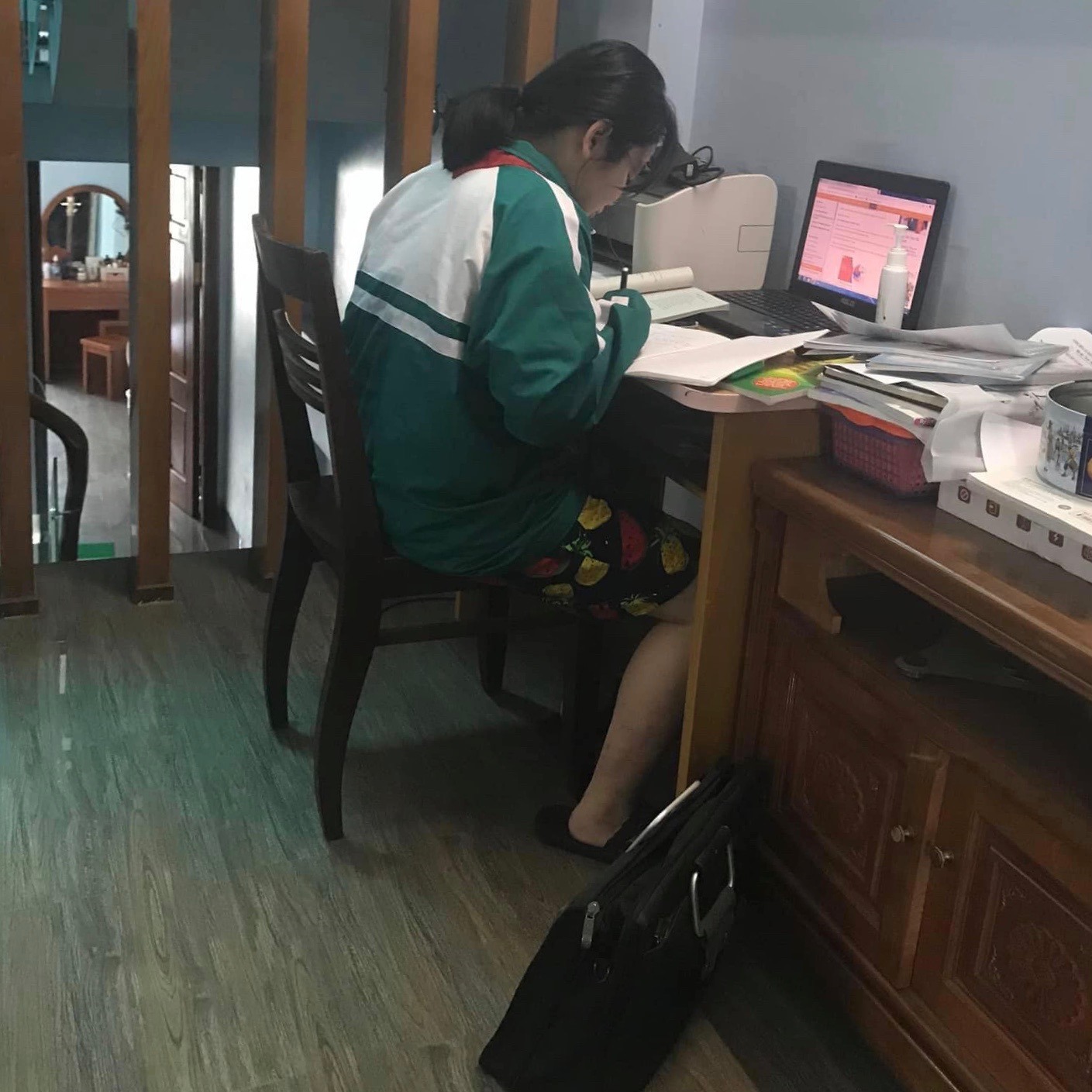 Học sinh nghiêm túc, mặc áo đồng phục, đeo khăn quàng đỏ ngồi học online ở nhà.