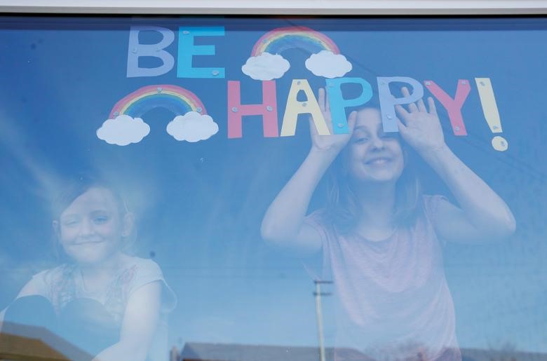Sophie và Emily Ward tạo dáng cùng với dòng chữ tô màu 7 sắc cầu vồng “Be Happy” (Hãy vui lên) ở Helens, Anh. Ảnh: Reuters
