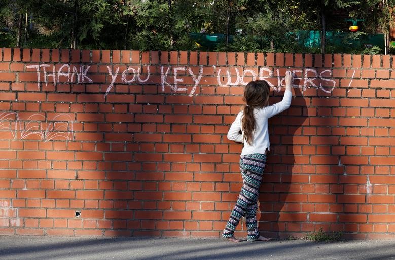 Một bé gái viết thông điệp “Thank you key workers” (Cảm ơn các bác sĩ ở tuyến đầu) để cổ vũ các nhân viên tuyến đầu ở High Wycombe, Anh. Ảnh: Reuters