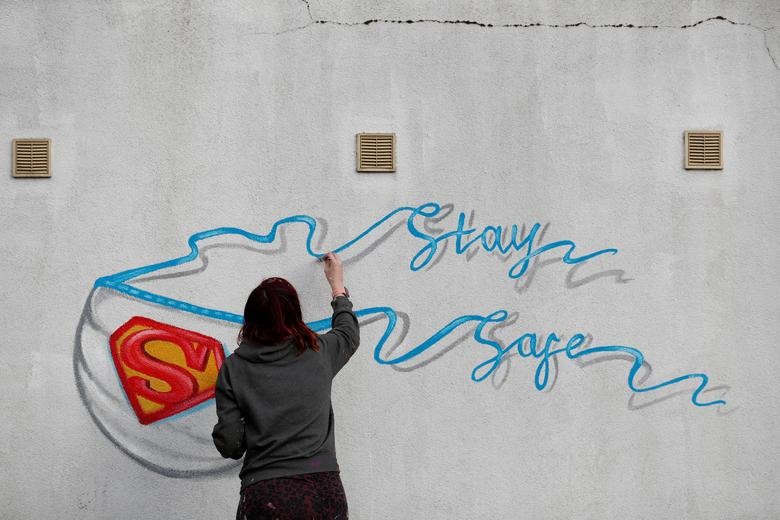 Nghệ sĩ Rachel List đang vẽ hình ảnh chiếc khẩu trang với thông điệp “Stay Safe” (Hãy ở nhà) ở thị trấn Pontefract, West Yorkshire, Anh. Ảnh: Reuters