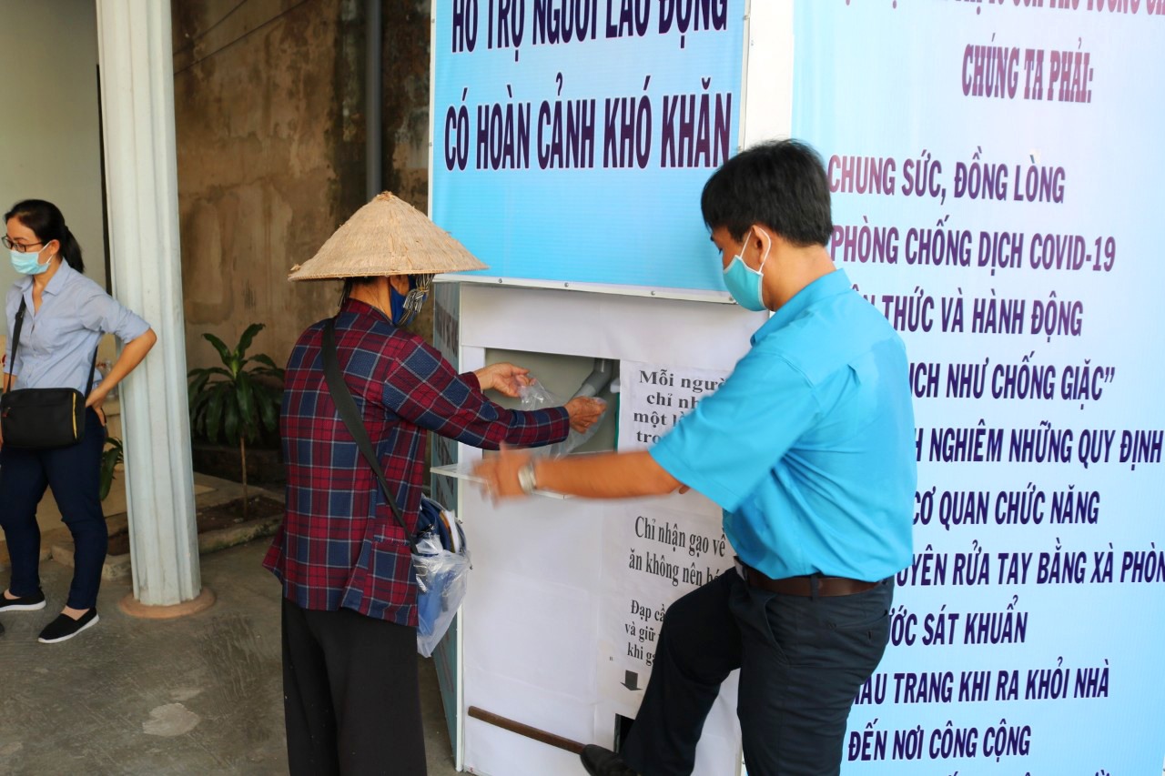 Cán bộ LĐLĐ huyện Phú Quốc tận tình hướng dẫn người lao động thao tác nhận gạo. Ảnh: LT