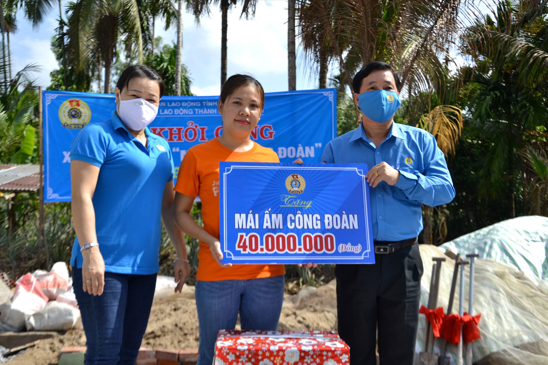 Ông Trần Thanh Việt (phải) trao biển tượng trưng hỗ trợ 40 triệu đồng và quà tặng của LĐLĐ Kiên Giang cho đoàn viên Nguyễn Thị Mai. Ảnh: LT