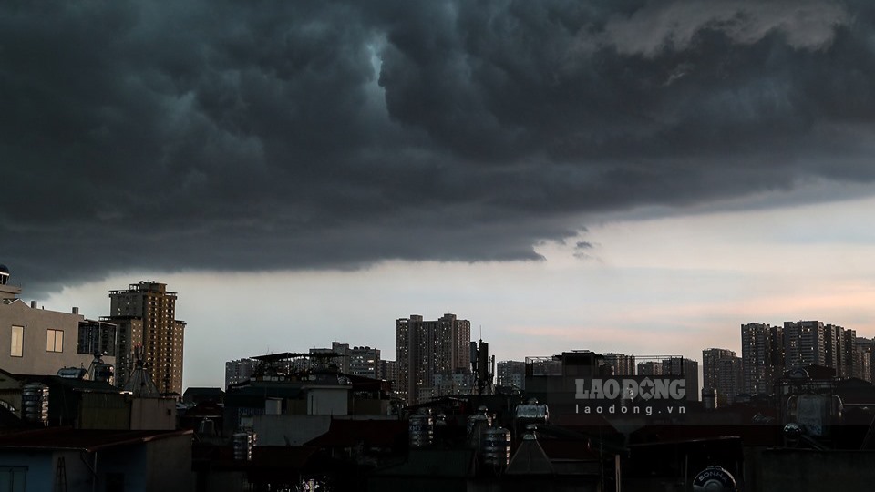 Bầu trời khu vực nội thành Hà Nội tối sầm, kèm theo mưa dông và gió giật mạnh.