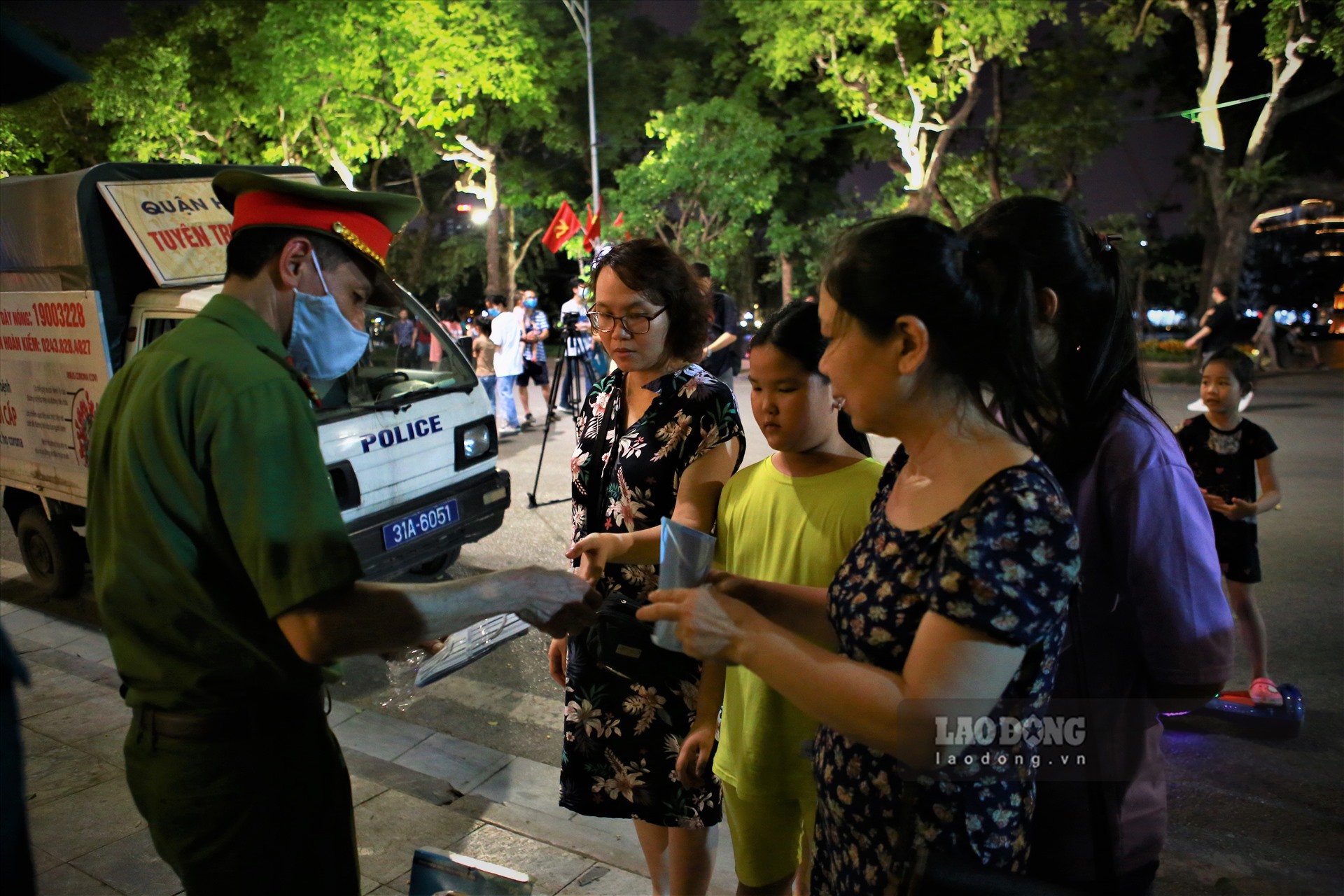 Lực lượng chức năng tại khu vực hồ Hoàn Kiếm phát khẩu trang miễn phí cho người dân đến phố đi bộ để phòng tránh dịch COVID-19.