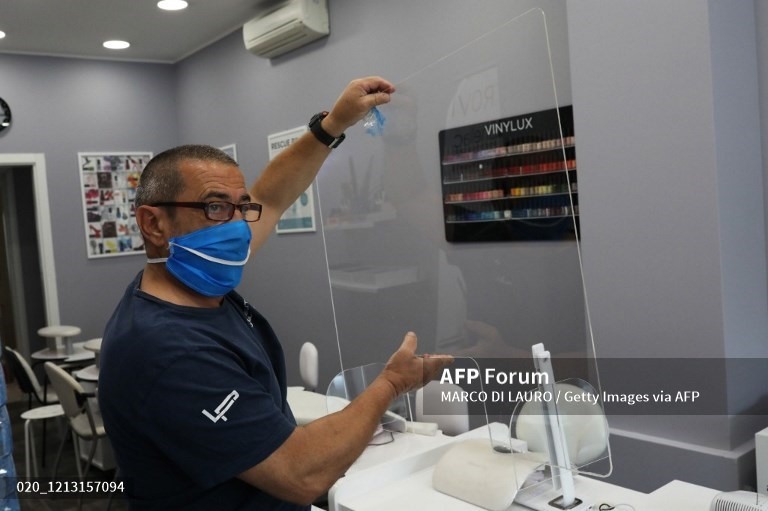 Một kỹ thuật viên lắp đặt thêm các tấm kính trong suốt tại trung tâm làm đẹp HS để ngăn ngừa lây lan COVID-19, tại Rome, Italia, ngày 15.5. Ảnh: AFP