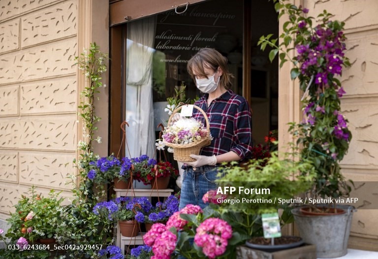 Một người bán hoa đeo khẩu trang làm việc trong cửa hàng  hoa tại Torino, Italia. Ảnh: AFP