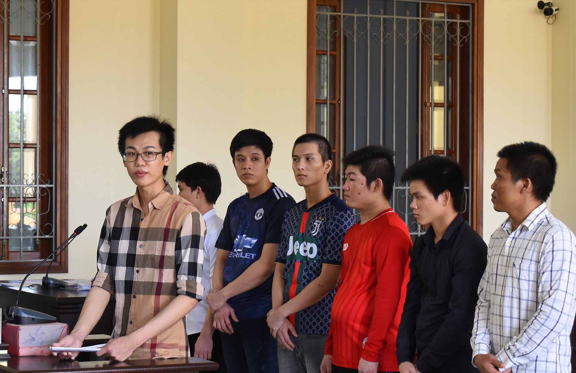 Bị cáo Nguyễn Phi Thông (đứng trước) và các bị cáo tại phiên tòa sơ thẩm. Ảnh: Thành Nhân