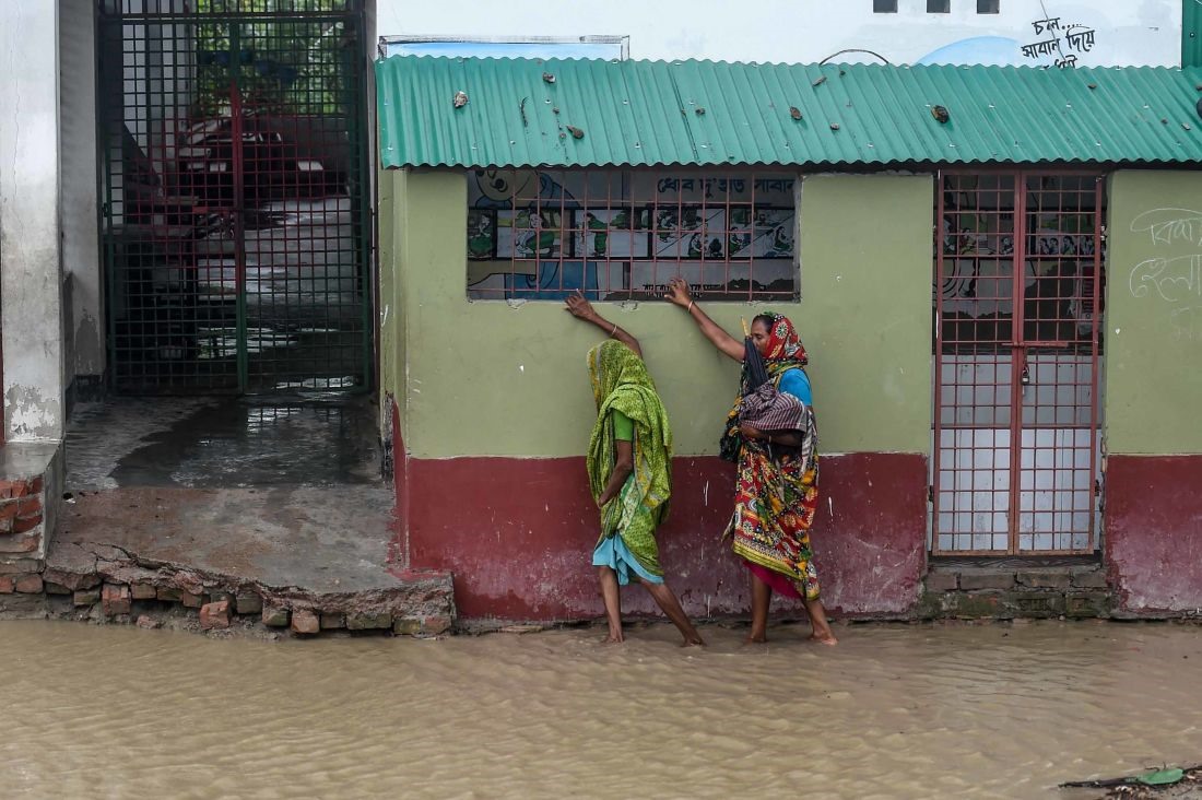 Cư dân đi bộ dọc theo dãy nhà trên con đường bị ngập lụt ở Dacope, Bangladesh. Ảnh: AFP