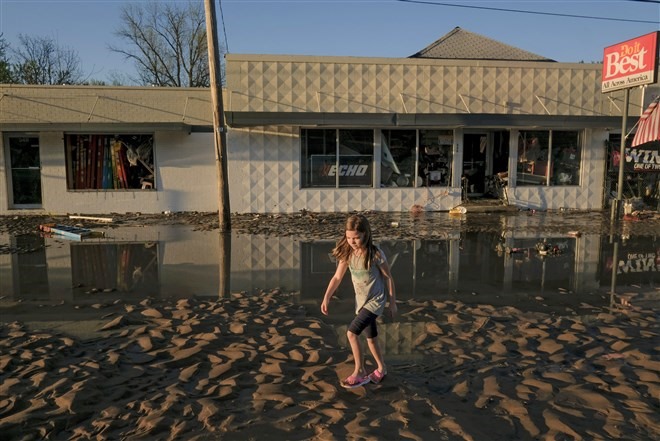Một cô gái đi trên con đường đầy bùn đất sau khi lũ rút đi ở Sanford, Michigan. Ảnh: AFP