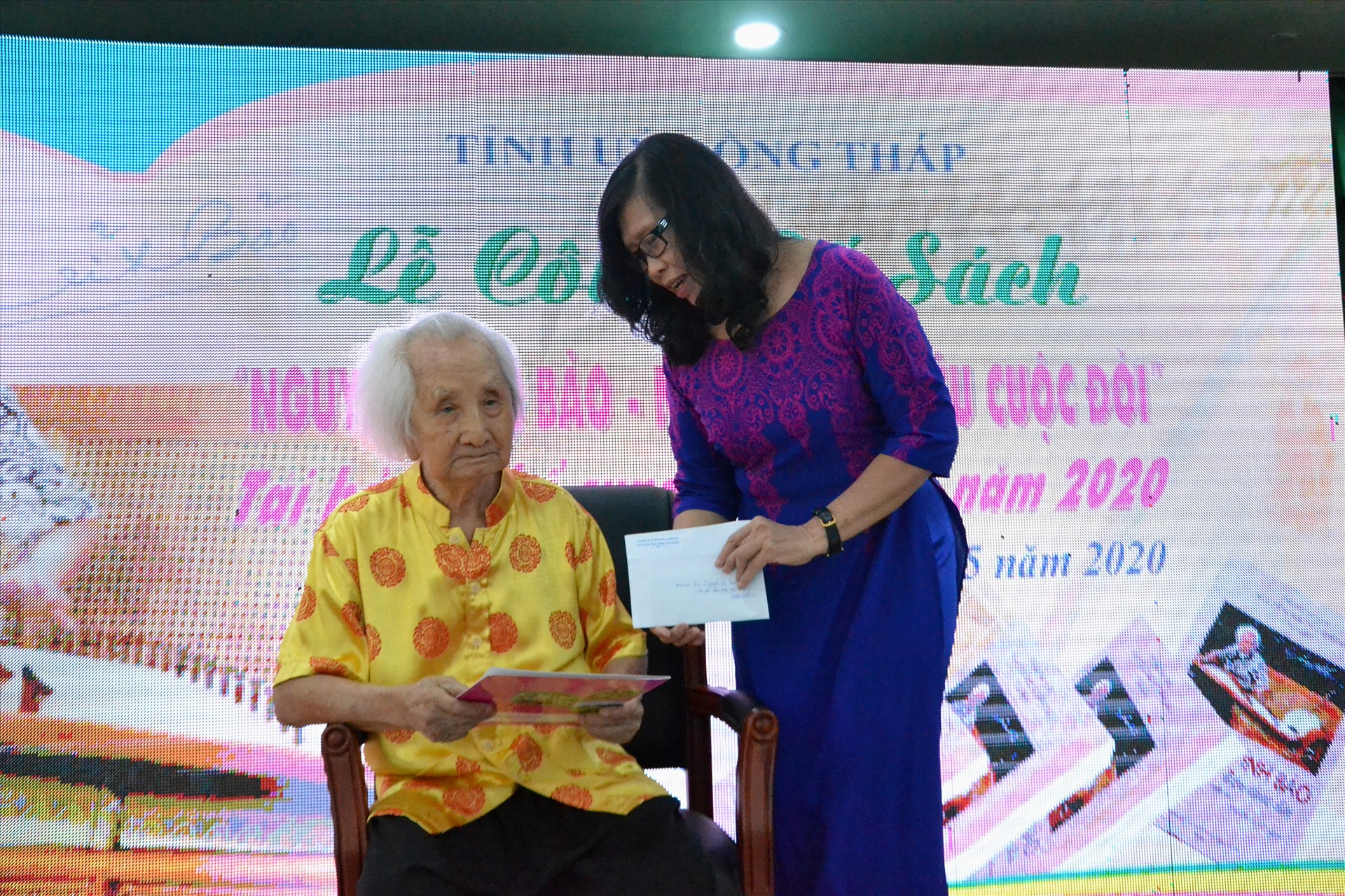 Thay mặt nhóm tác giả, tiến sĩ Nguyễn Thị Kim Ửng trao toàn bộ tiền nhuận bút cho nhạc sư. Ảnh: LT