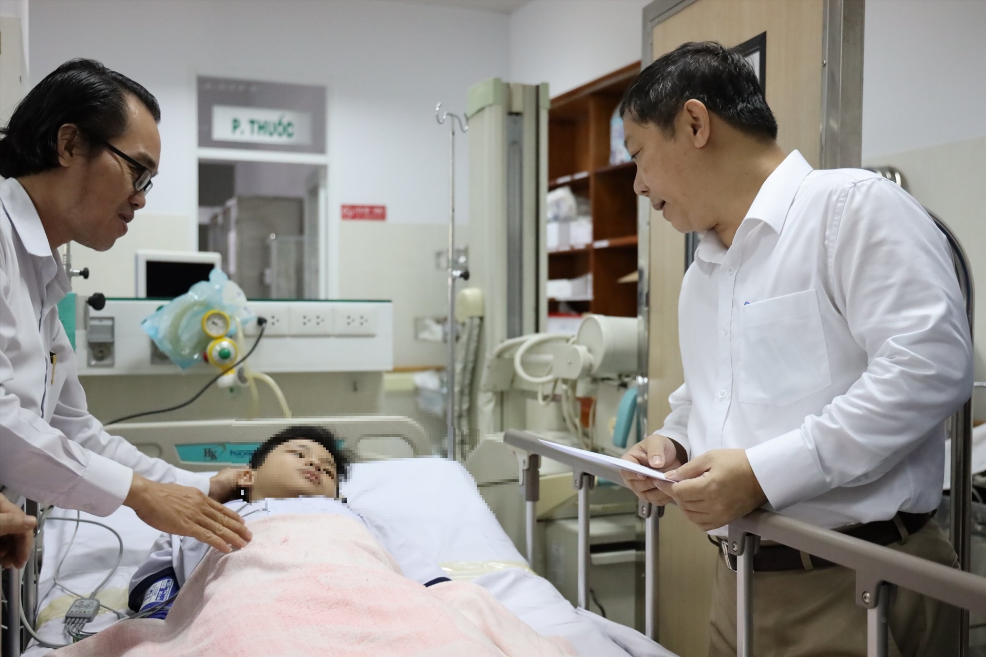 Dương Anh Đức (bên phải) hỏi han 1 em học sinh đang điều trị tại Bệnh viện Nhi đồng 2. Ảnh: Thanh Hà
