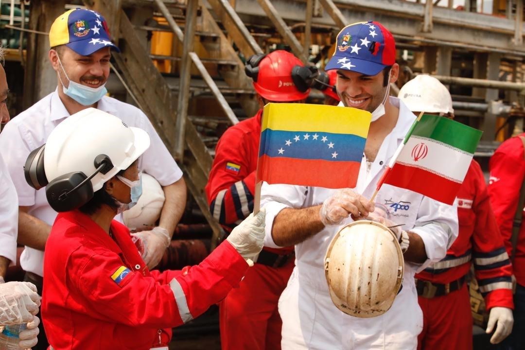 Công nhân cầm cờ Venezuela và Iran chào đón tàu Iran Fortune. Ảnh: EPA