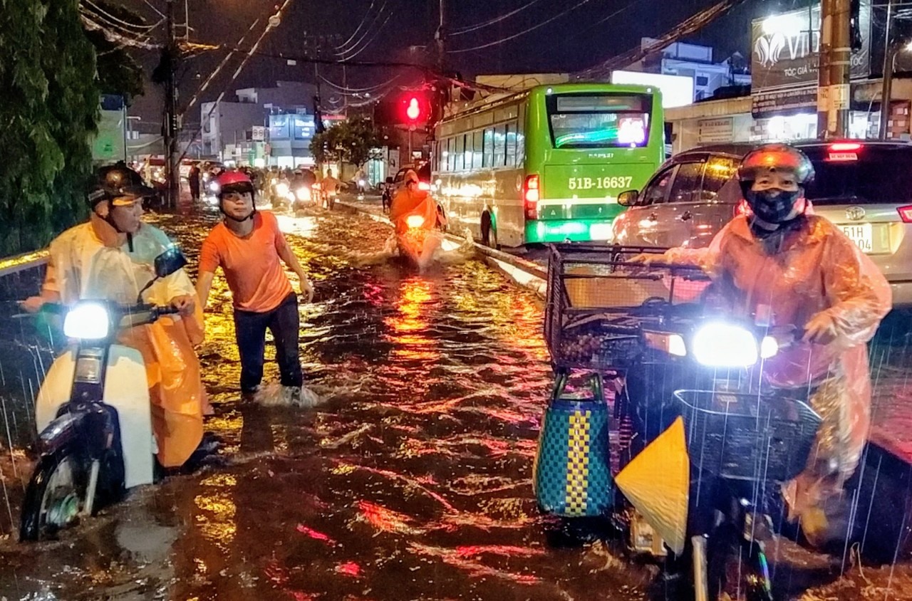 Người dân hì hục dắt xe máy về nhà sau mưa lớn.  Ảnh: Minh Quân