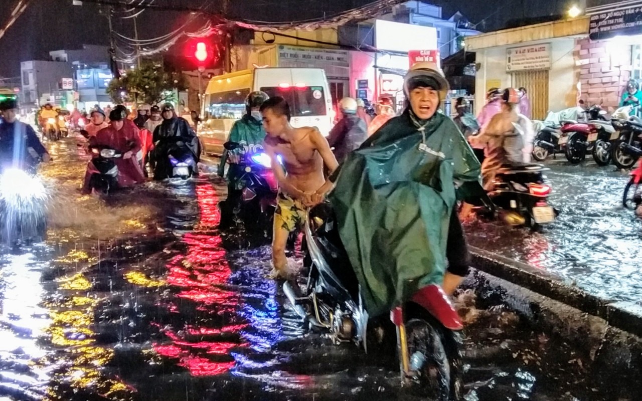 Hì hục xe chết may qua đoạn ngập, chị Nguyễn Thị Bình (quận Thủ Đức) nói: “Đoạn đường này khá trũng, cứ mưa lớn là như một cái ao“.  Ảnh: Minh Quân