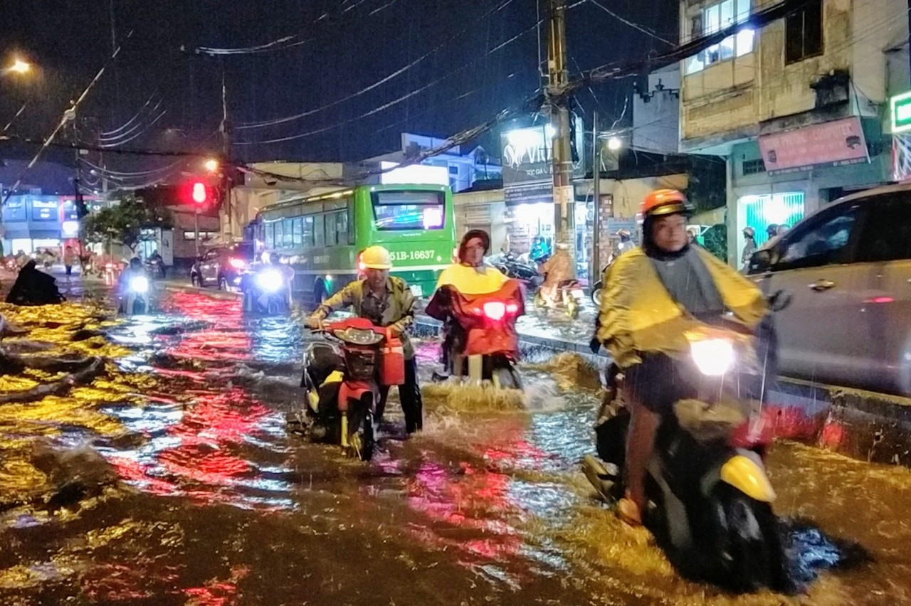 Người dân bì bõm lội nước, dắt xe chết máy trên đường Tô Ngọc Vân.  Ảnh: Minh Quân