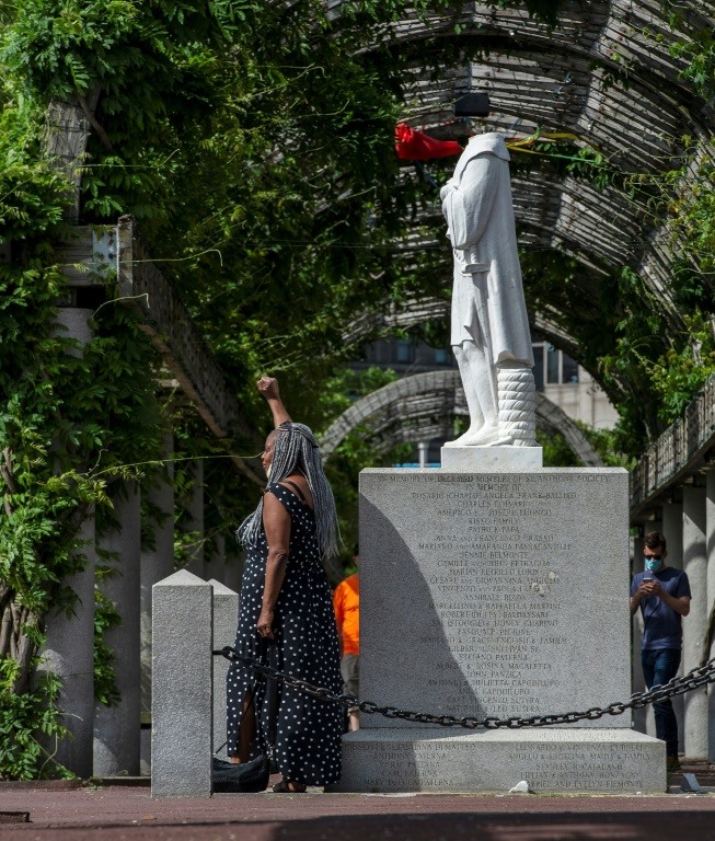 Một người phụ nữ tạo dáng trước bức tượng Columbus bị chặt đầu tại Công viên Christopher Columbus ở Boston, Massachusetts vào ngày 10.6. Ảnh: AFP