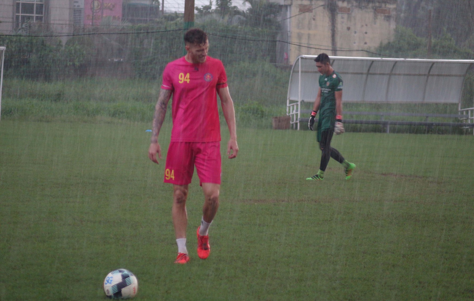 Tiền đạo Geovane và thủ môn Phạm Văn Phong nhanh chóng di chuyển vào trong xe khi trời đổ mưa như trút nước. Ảnh: Nguyễn Đăng.