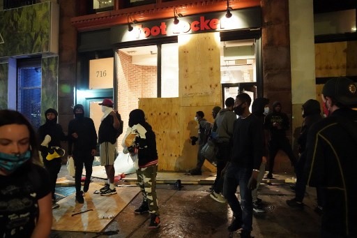 Những kẻ phá hoại đột nhập một cửa hàng dù đã niêm phong kín, ngày 1.6 tại New York. Ảnh: AFP