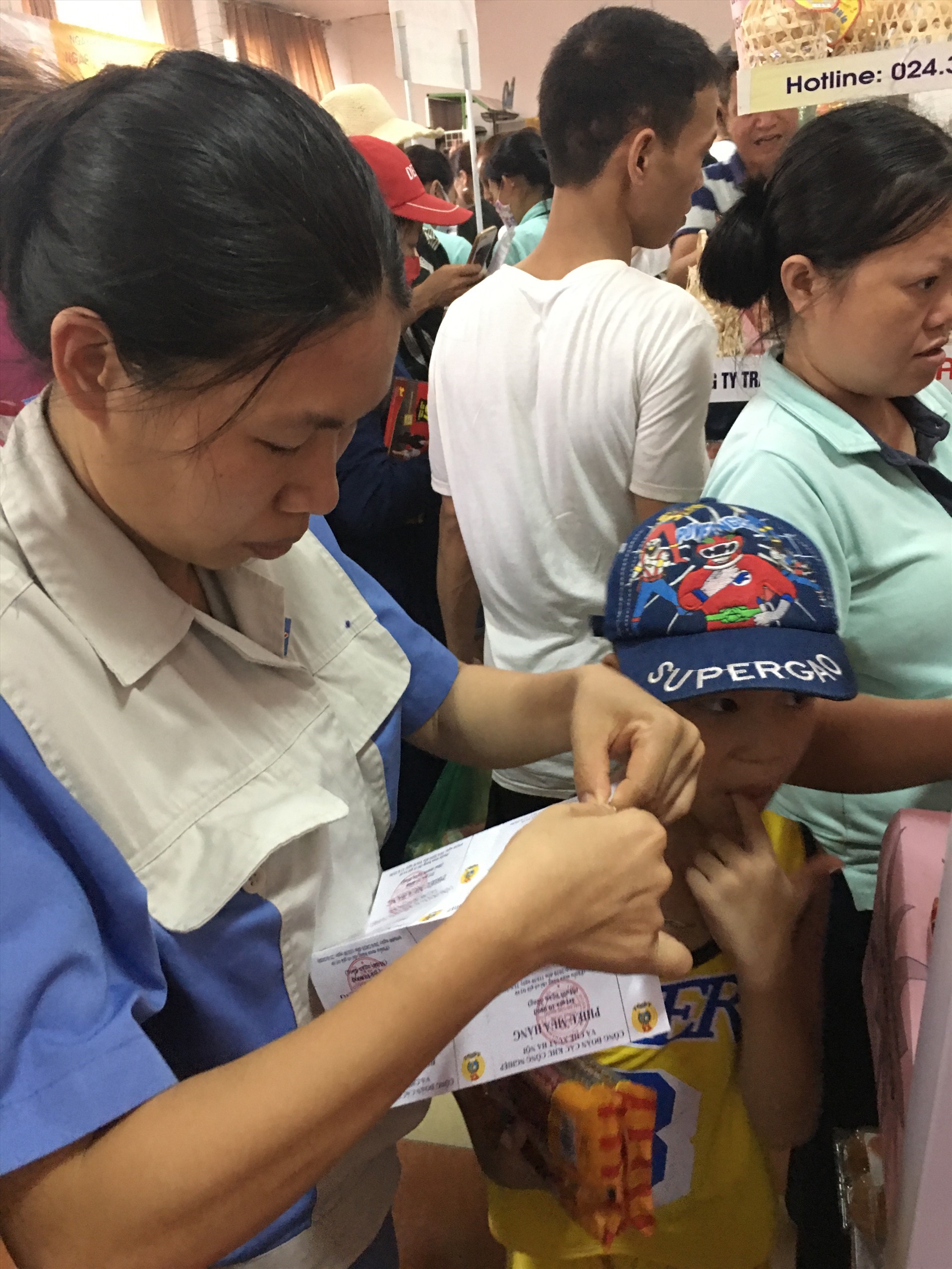 Một nữ công nhân mất việc dùng phiếu mua hàng được phát để mua xúc xích cho con tại “Siêu thị giá 0 đồng” do Công đoàn các KCN-CX Hà Nội tổ chức ngày 20-21.6. Ảnh: T.E.A