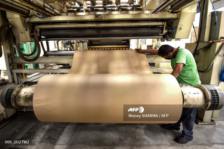 Từng cuộn giấy bìa các tông sẽ đưa vào xử lý bằng máy công nghiệp do các công nhân vận hành để tiết kiệm sức lao động. Ảnh: AFP.