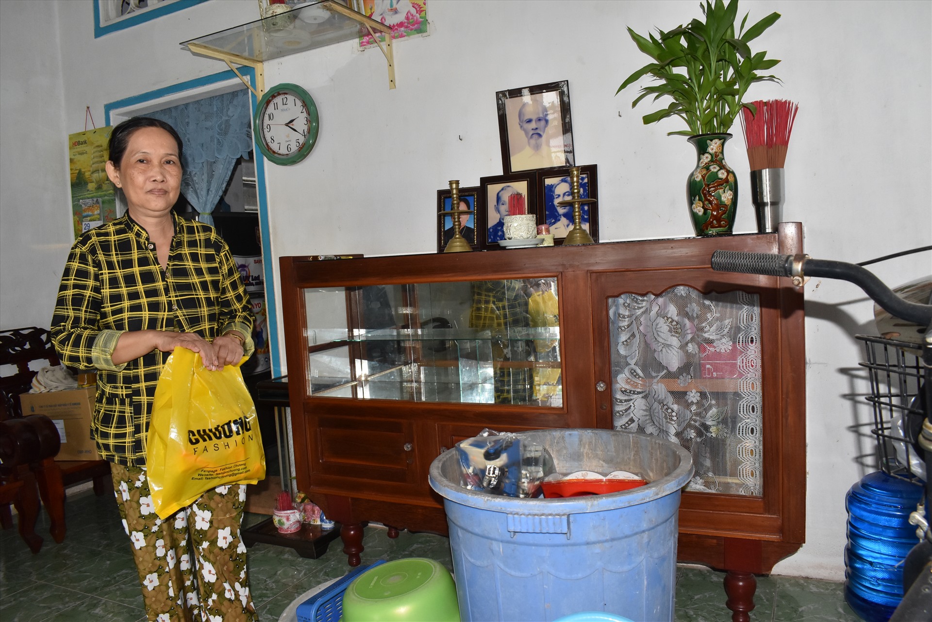 Vợ ông Nguyễn Công Quy thu dọn đồ đạc để chuẩn bị di dời bất cứ lúc nào. Ảnh: Thành Nhân