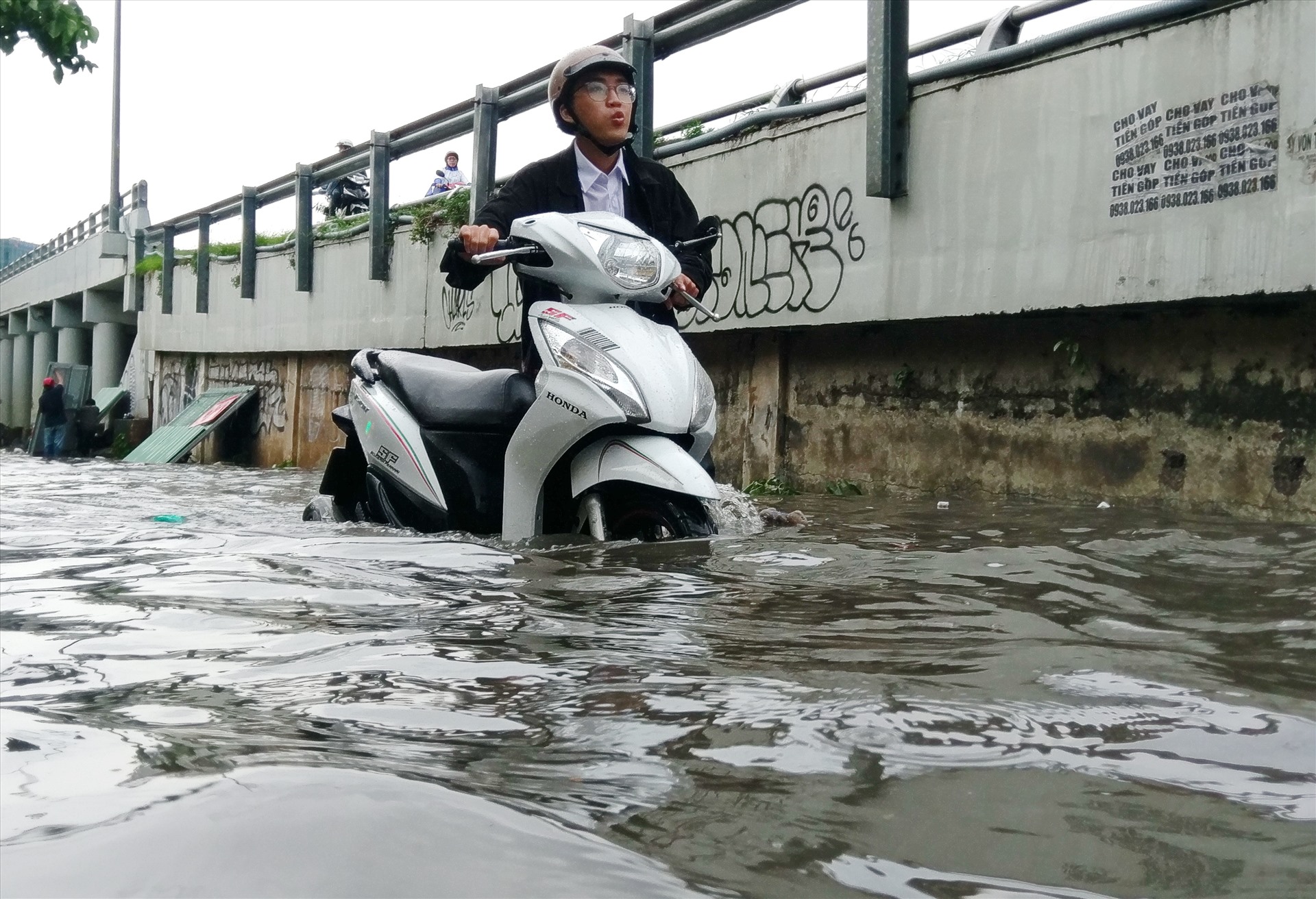 Ngập nước khiến hàng loạt xe chết máy, người dân phải đẩy bộ phương tiện bì bõm giữa dòng nước.