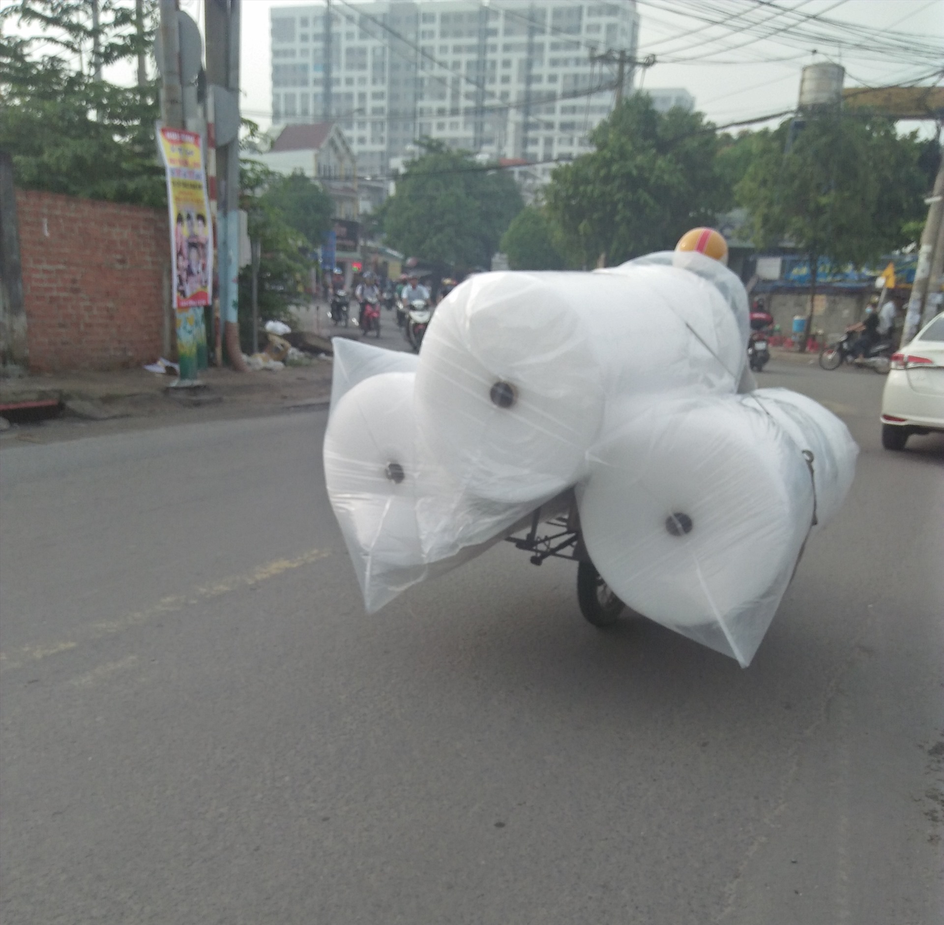 Người đi xe máy chở 3 cuộn hàng cồng kềnh chạy như xiếc trên đường Đào Trinh Nhất, Thủ Đức, TPHCM ( ảnh chụp sáng 30.6). Ảnh: Minh Khang