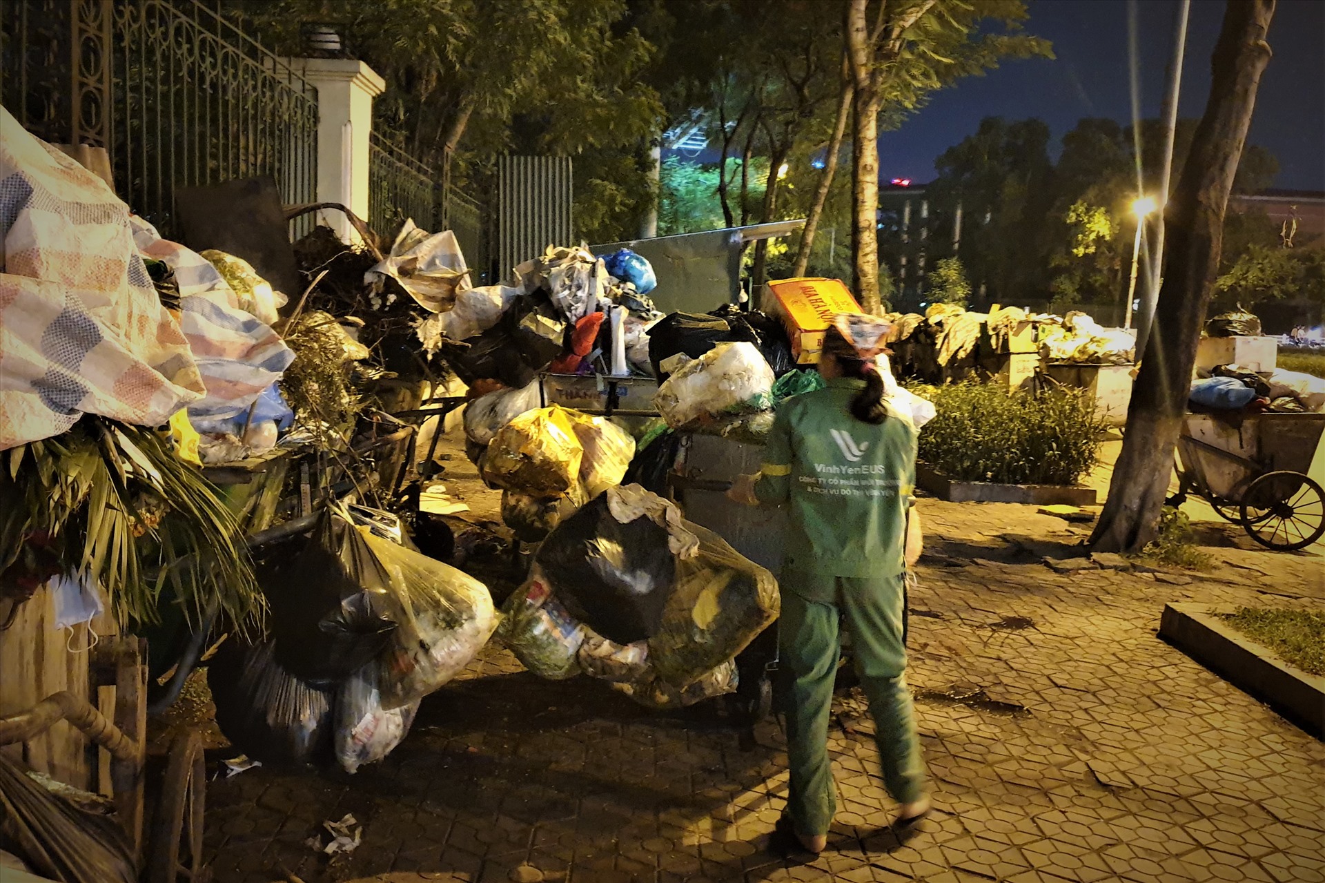 Công nhân đẩy những chiếc xe gom rác đầy ắp rác thải.