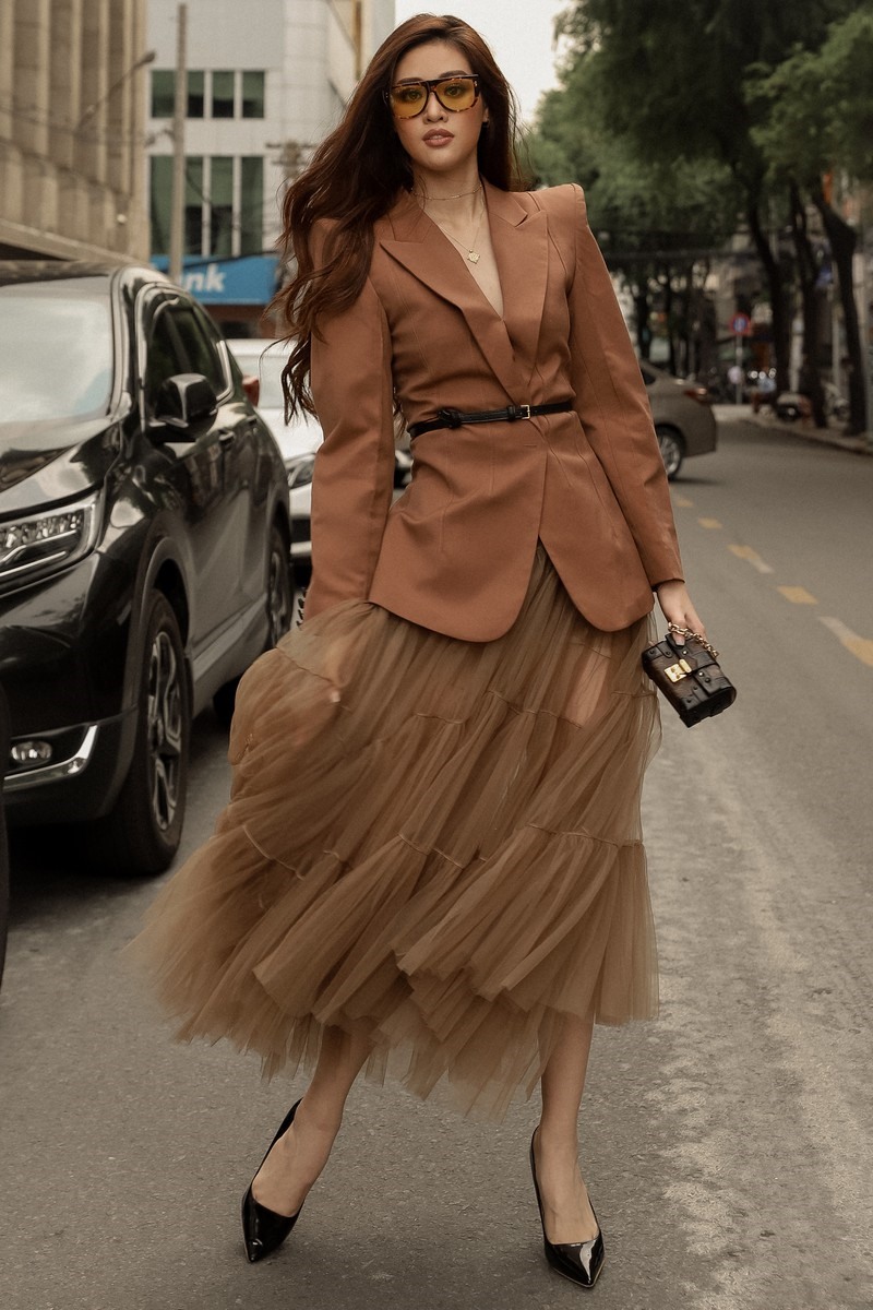 Ở set trang phục của Accent Concept, Hoa hậu Khánh Vân đặc biệt ấn tượng bởi sự kết hợp giữa áo vest nâu và chân váy xoè xếp tầng  Với set đồ này, Khánh Vân có thể áp dụng cho nhiều hoạt động khác nhau.