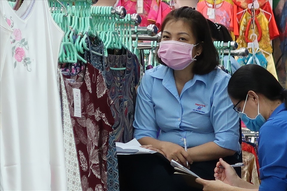 Một số nhân viên kinh doanh tại chợ Bến Thành đeo khẩu trang và thực hiện tờ khai lịch trình của cá nhân và gia đình trong 14 ngày gần nhất. - Ảnh Hữu Huy