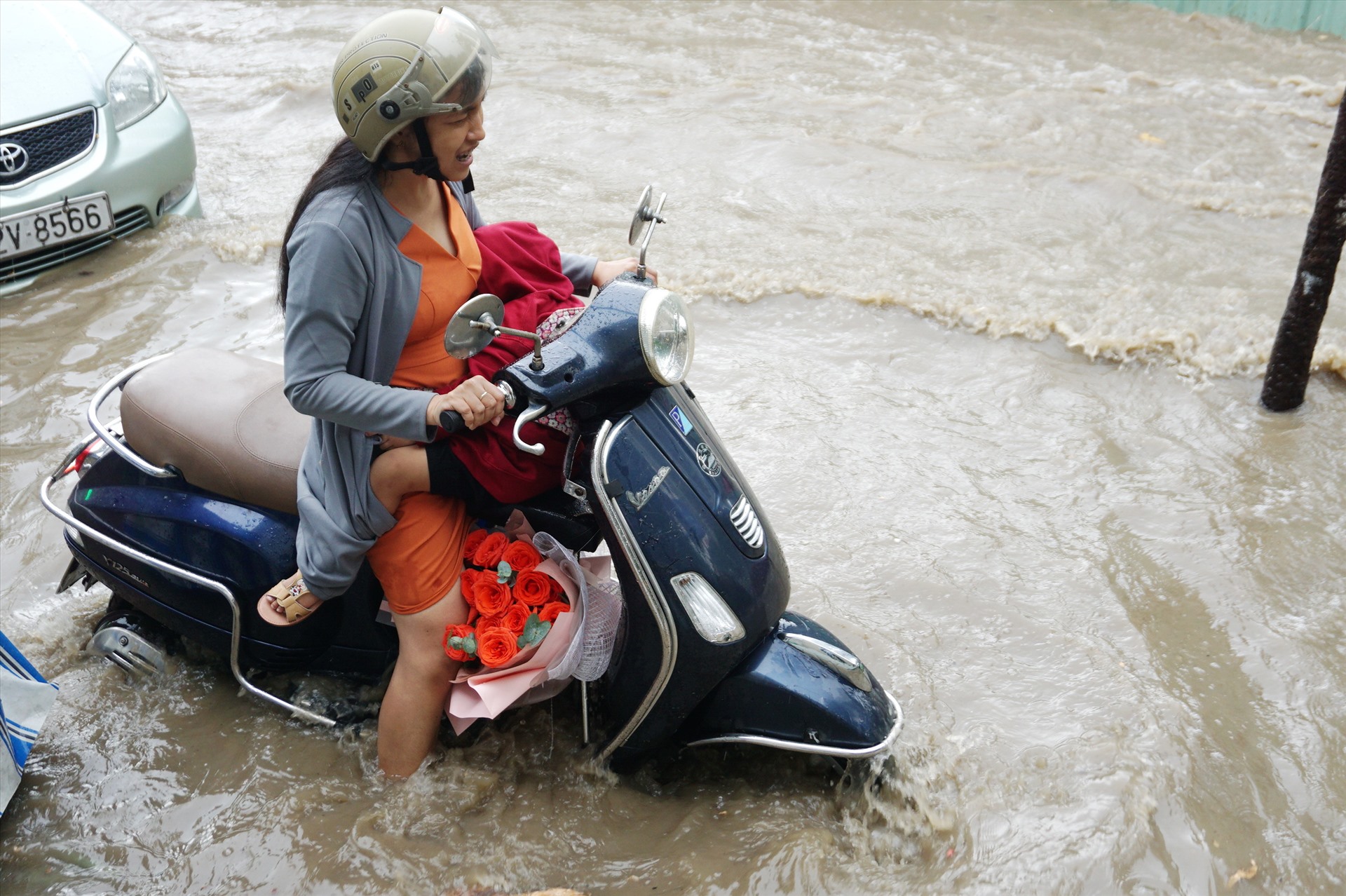 Một em nhỏ ôm chặt lấy mẹ khi chiếc xe máy của hai mẹ con chết máy giữa dòng nước ngập trên đường Nguyễn Hữu Cảnh.  Ảnh: Minh Quân