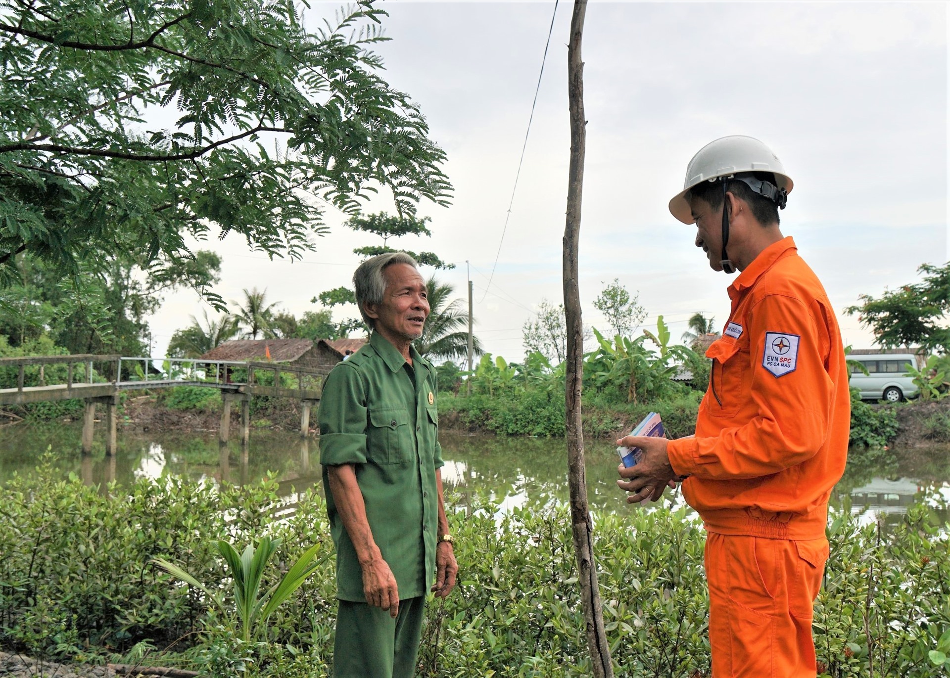 Nhân viên điện lực tuyên truyền, khuyến khích người dân vùng nông thôn tại xã Phong Lạc, huyện Trần Văn Thời, tỉnh Cà Mau, sử dụng điện an toàn sau điện kế nhằm giảm thiểu tai nạn điện. Ảnh EVNSPC cung cấp.