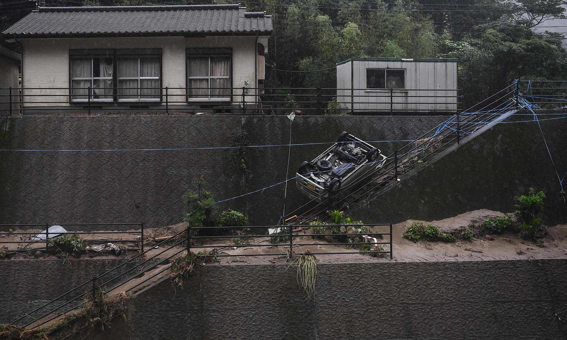 Một chiếc ô tô bị lật ở khu vực bị mưa lớn ở Ashikita, quận Kumamoto. Ảnh AFP.