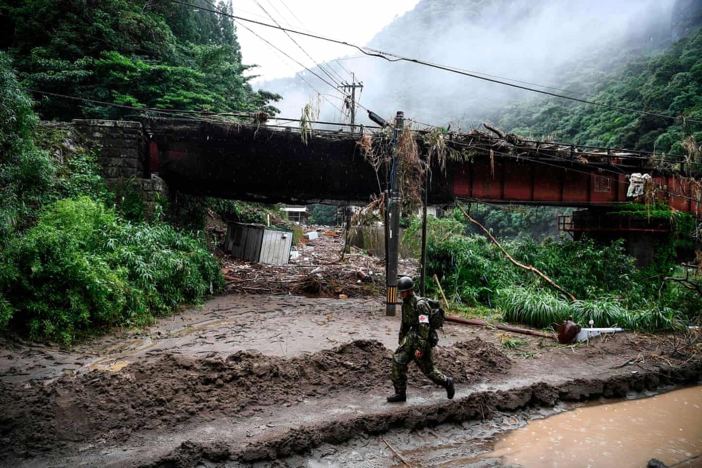 Một người lính đi bộ trong một khu vực bị mưa lớn ở Ashikita. Ảnh: AFP