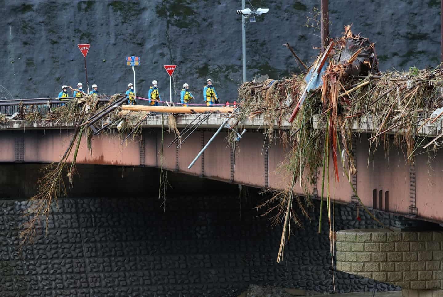 Nhân viên cứu trợ đi bộ qua các mảnh vỡ trên cầu Kuma sau cơn mưa xối xả ở quận Kumamoto. Ảnh AFP.