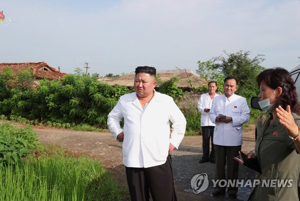 Nhà lãnh đạo Triều Tiên đang lắng nghe một quan chức thông tin về tình hình trong chuyến thăm ngôi làng bị lũ lụt. Theo truyền thông nhà nước Triều Tiên thông tin ngày 10.8, ông Kim Jong-un cam kết sẽ xuất ngũ cốc từ nguồn dự trữ đặc biệt cho người dân vùng lũ trong chuyến thăm hồi tuần trước tới vùng Taechong-ri của huyện Unpha, tỉnh Hwanghae Bắc. Taechong-ri  là khu vực có hơn 900 ngôi nhà, 600 ruộng lúa bị ngập trong nước lũ sau khi một con đê bị vỡ. Ảnh: Yonhap.