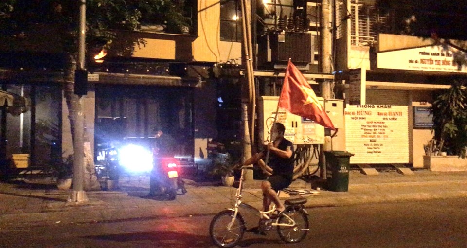 Sau khi hàng rào phong tỏa được tháo bỏ, một người dân vui mừng cầm cờ Tổ quốc thể hiện sự tự hào dân tộc. Ảnh: Mai Hương