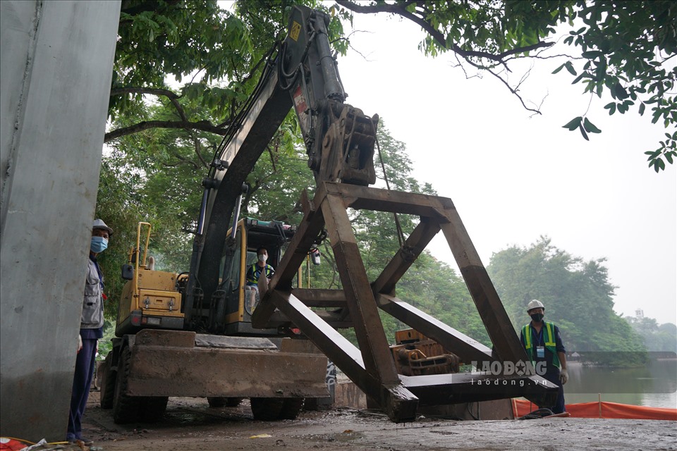 Theo quan sát, khoảng 10 công nhân dùng máy ép thủy lực lắp đặt cấu kiện bê tông cuối cùng của bờ kè.